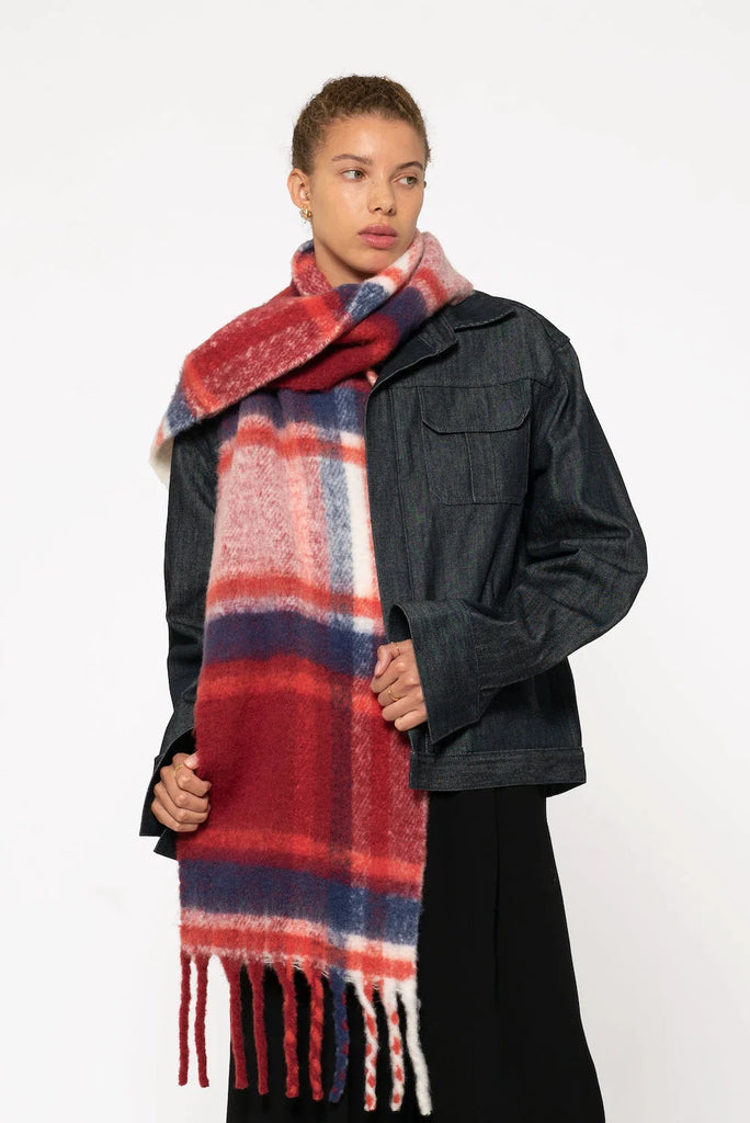 woman wearing oversized red & navy plaid scarf with tassels