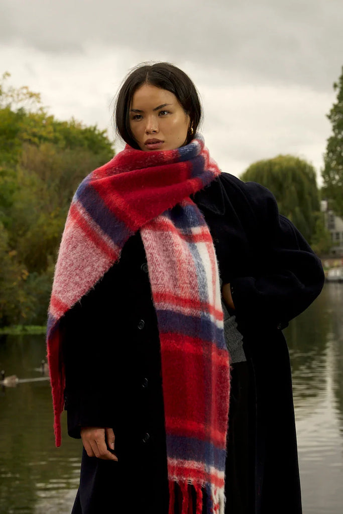 large red and blue scarf woman wearing oversized red & navy plaid scarf in front of canal