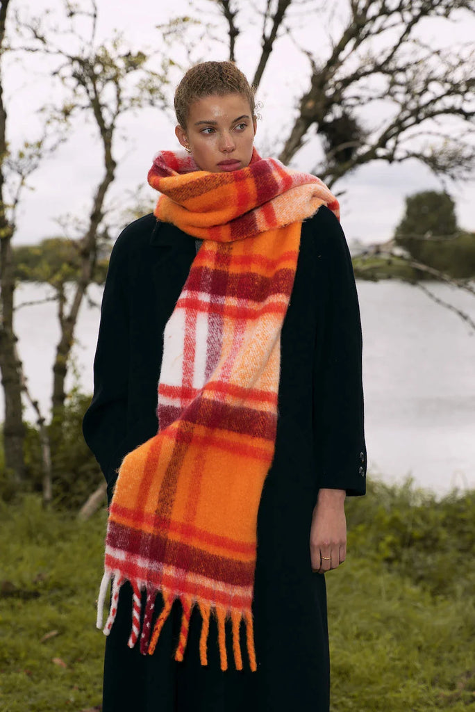 woman wearing chunky orange and red plaid scarf with tassels
