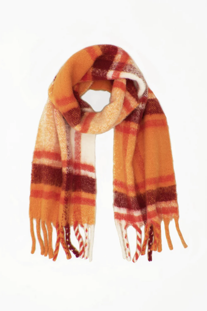 flat lay image of orange, red and white plaid scarf with soft fluffy material and tassels
